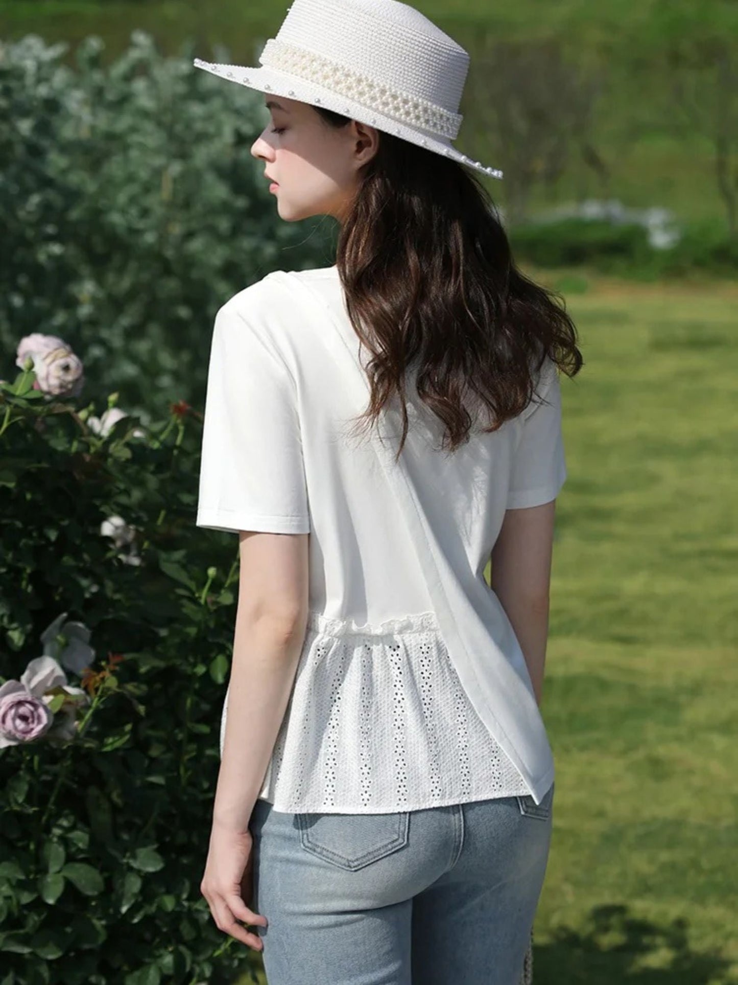 A woman wearing a pleated t-shirt with eyelet details.