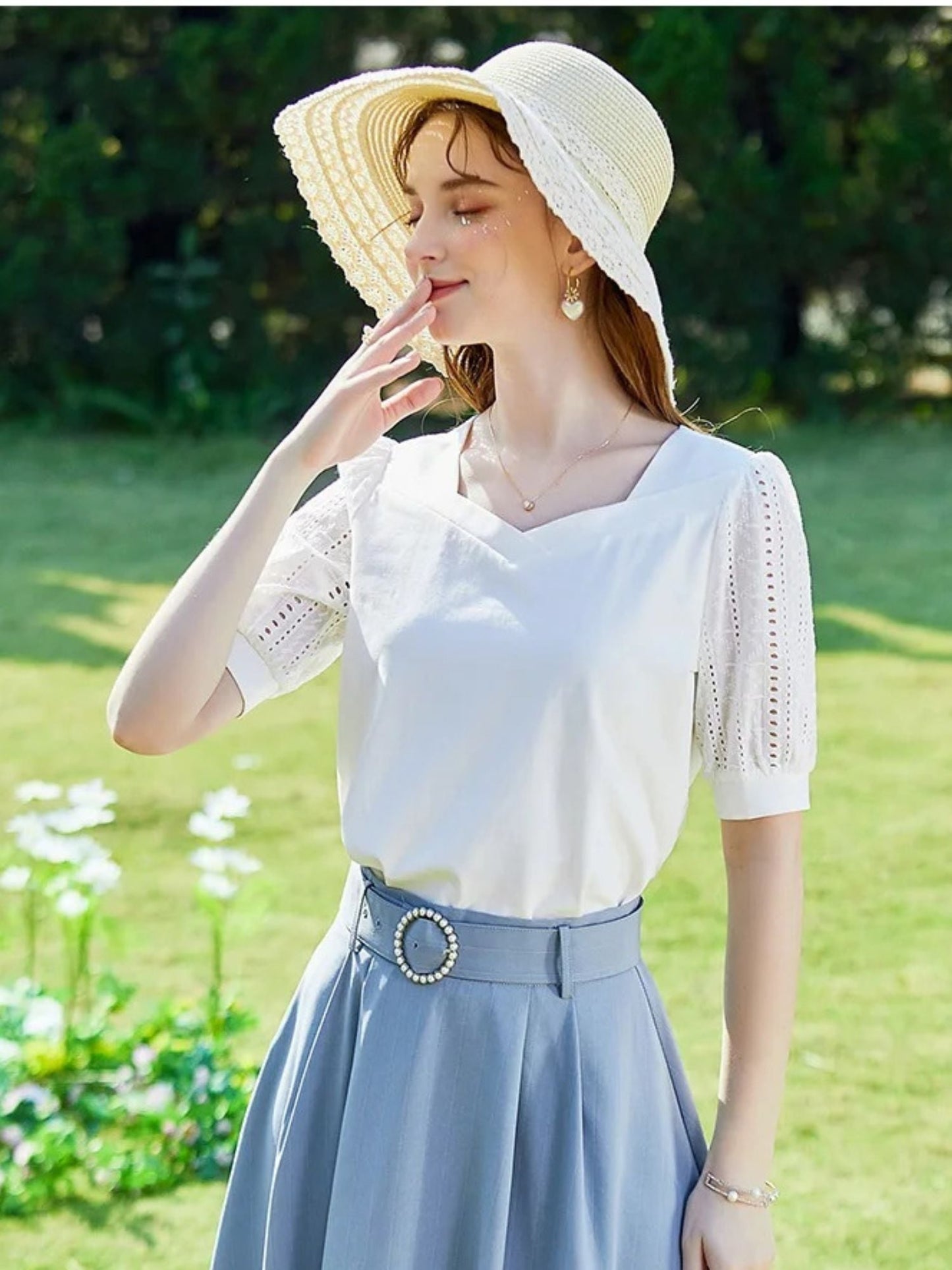 A woman wearing a summer blouse with eyelet ouff sleeves and a square neckline.