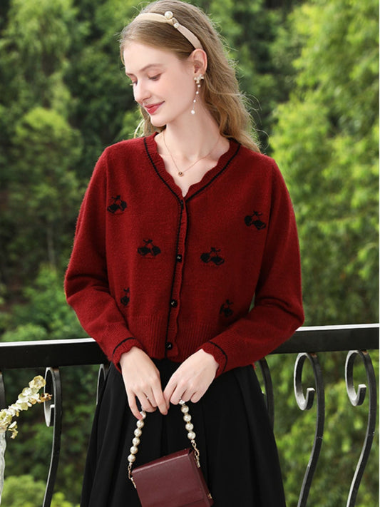 A woman wearing a red knit cardigan with embroidery.