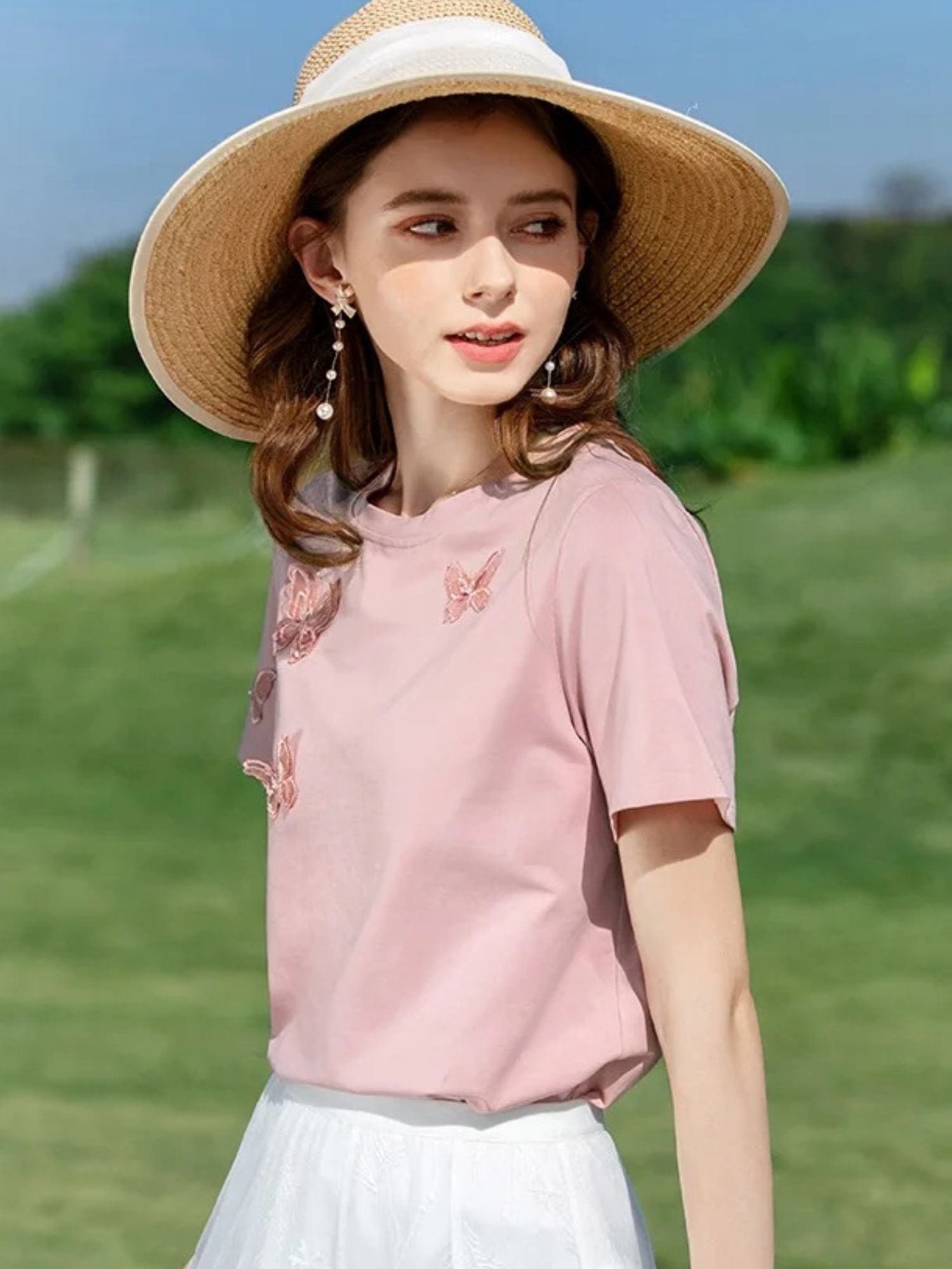 A woman wearing a summer t-shirt with a butterfly embroidery.