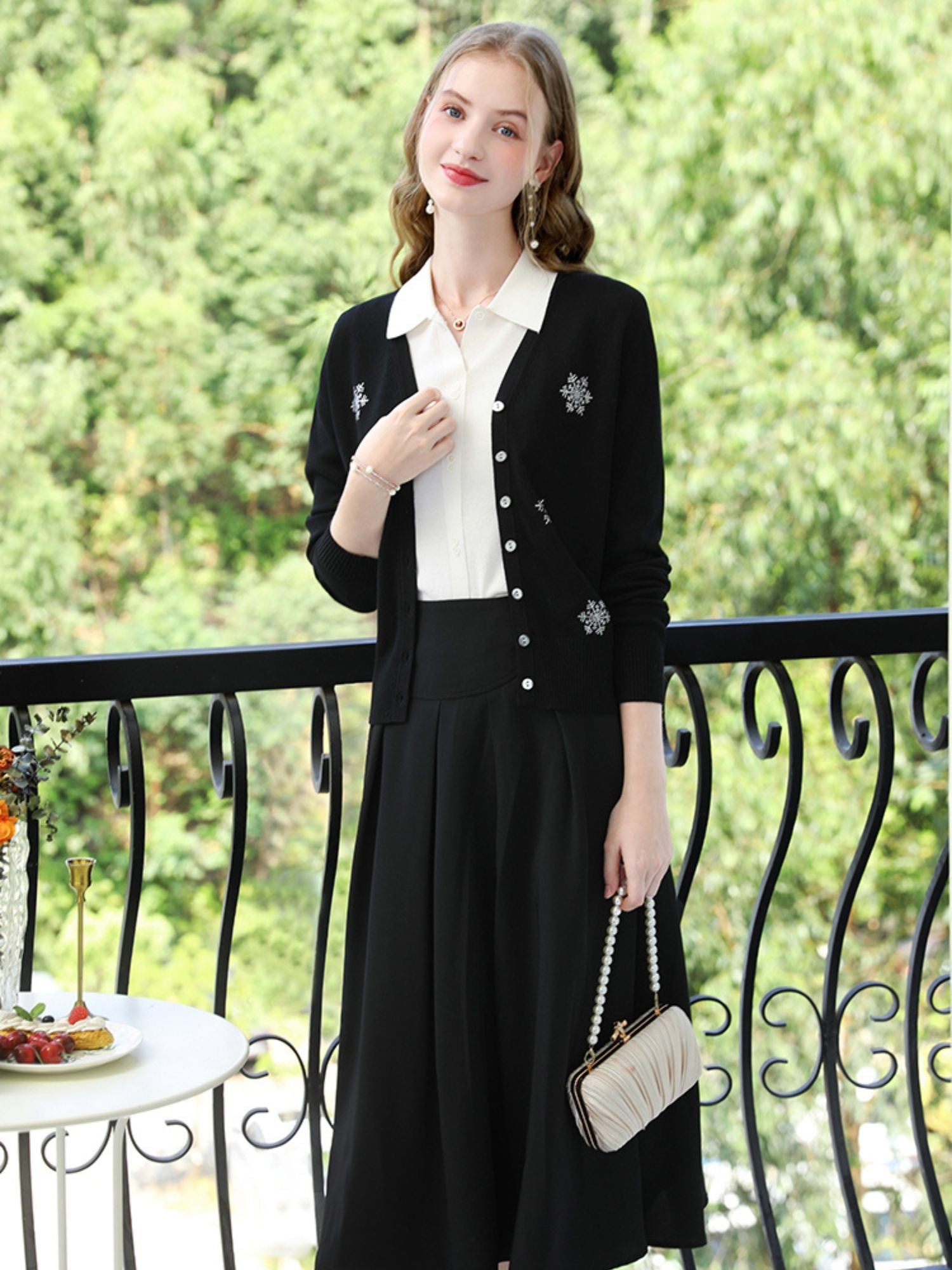 A woman wearing a v-neck cardigan with snowflakes embelishments.