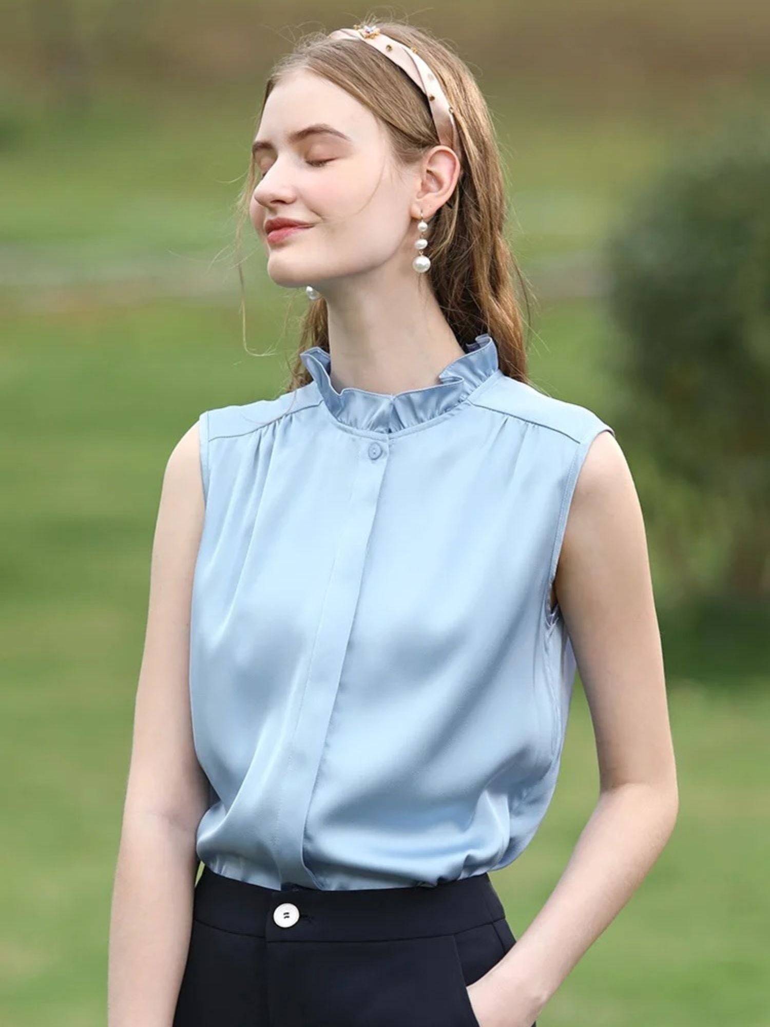 A woman wearing a sleeveless blouse with a ruffled collar design.