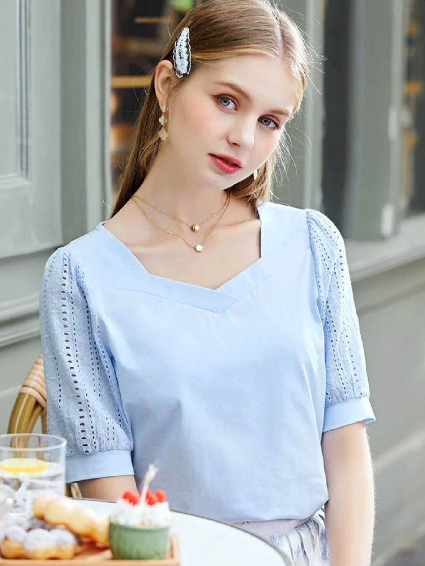 A woman wearing a summer blouse with eyelet ouff sleeves and a square neckline.