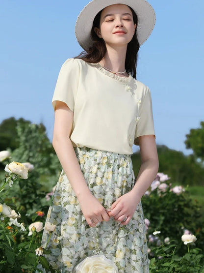 A woman wearing a floral chiffon midi skirt with a high elastic waistband, paired with a plain top, standing in a garden.