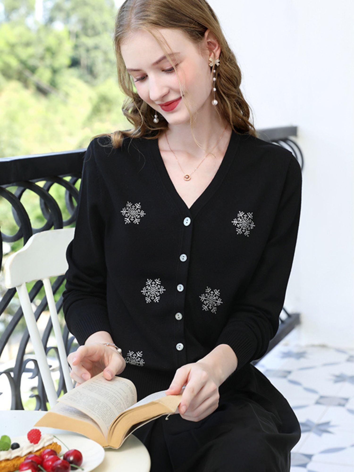 A woman wearing a v-neck cardigan with snowflakes embelishments.