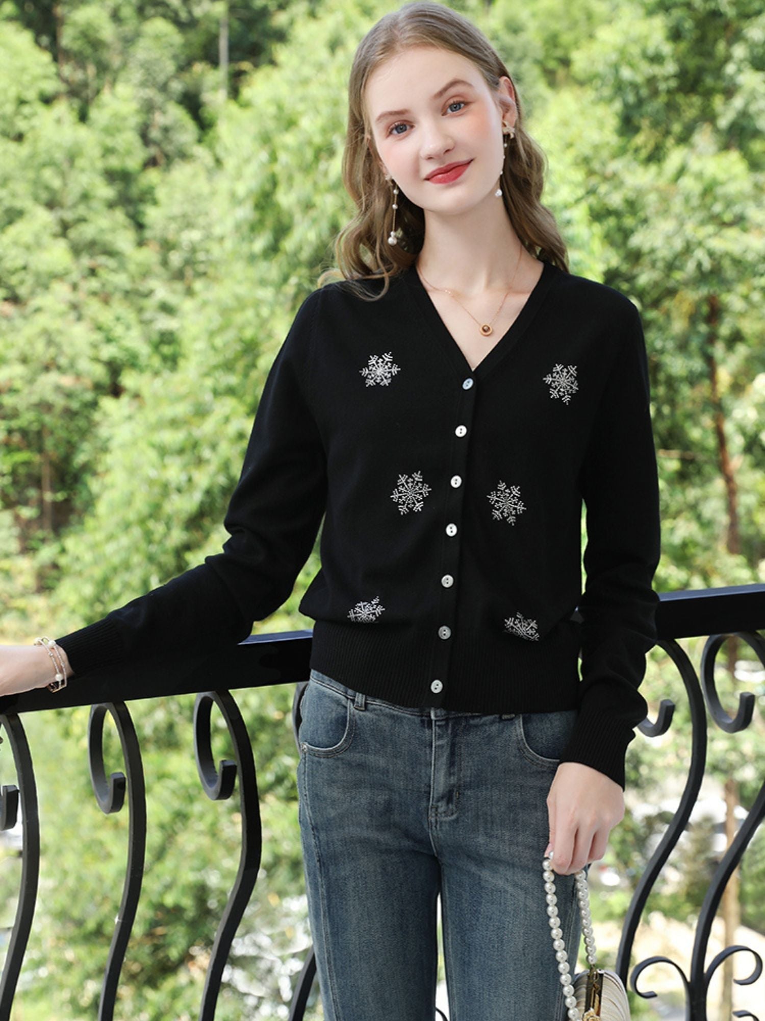 A woman wearing a v-neck cardigan with snowflakes embelishments.