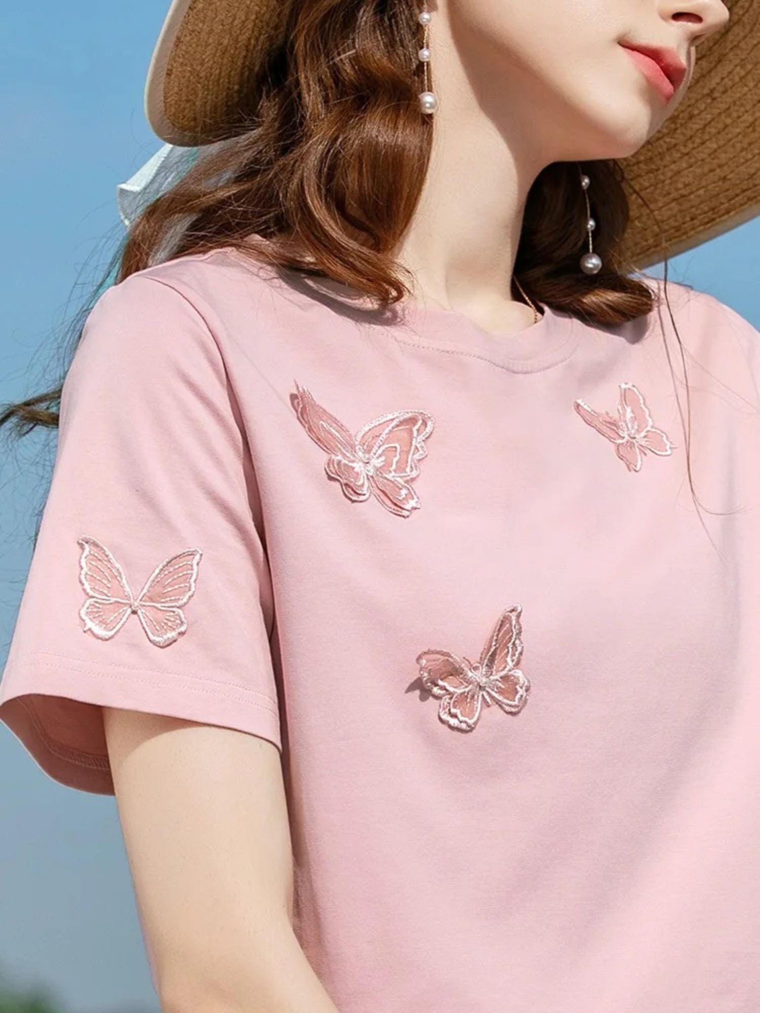 A woman wearing a summer t-shirt with a butterfly embroidery.