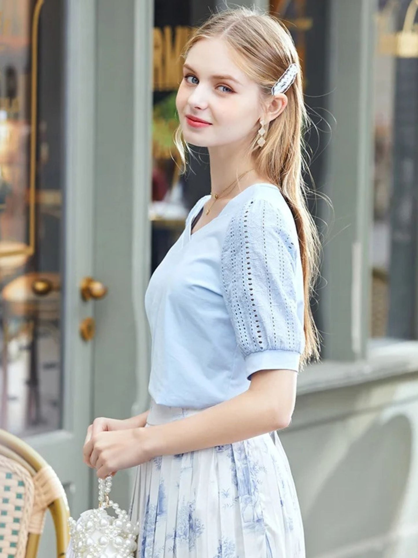 A woman wearing a summer blouse with eyelet ouff sleeves and a square neckline.