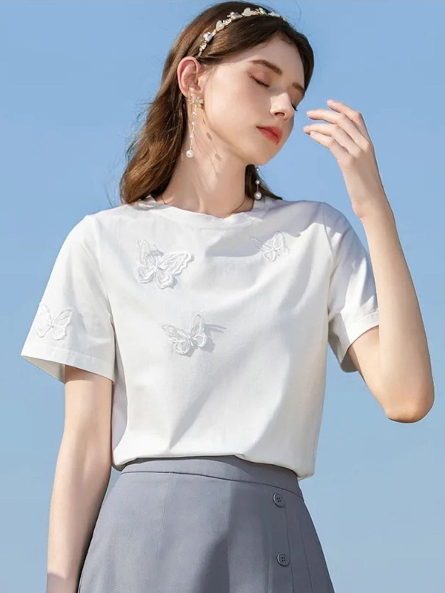 A woman wearing a summer t-shirt with a butterfly embroidery.