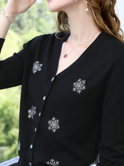 A woman wearing a v-neck cardigan with snowflakes embelishments.