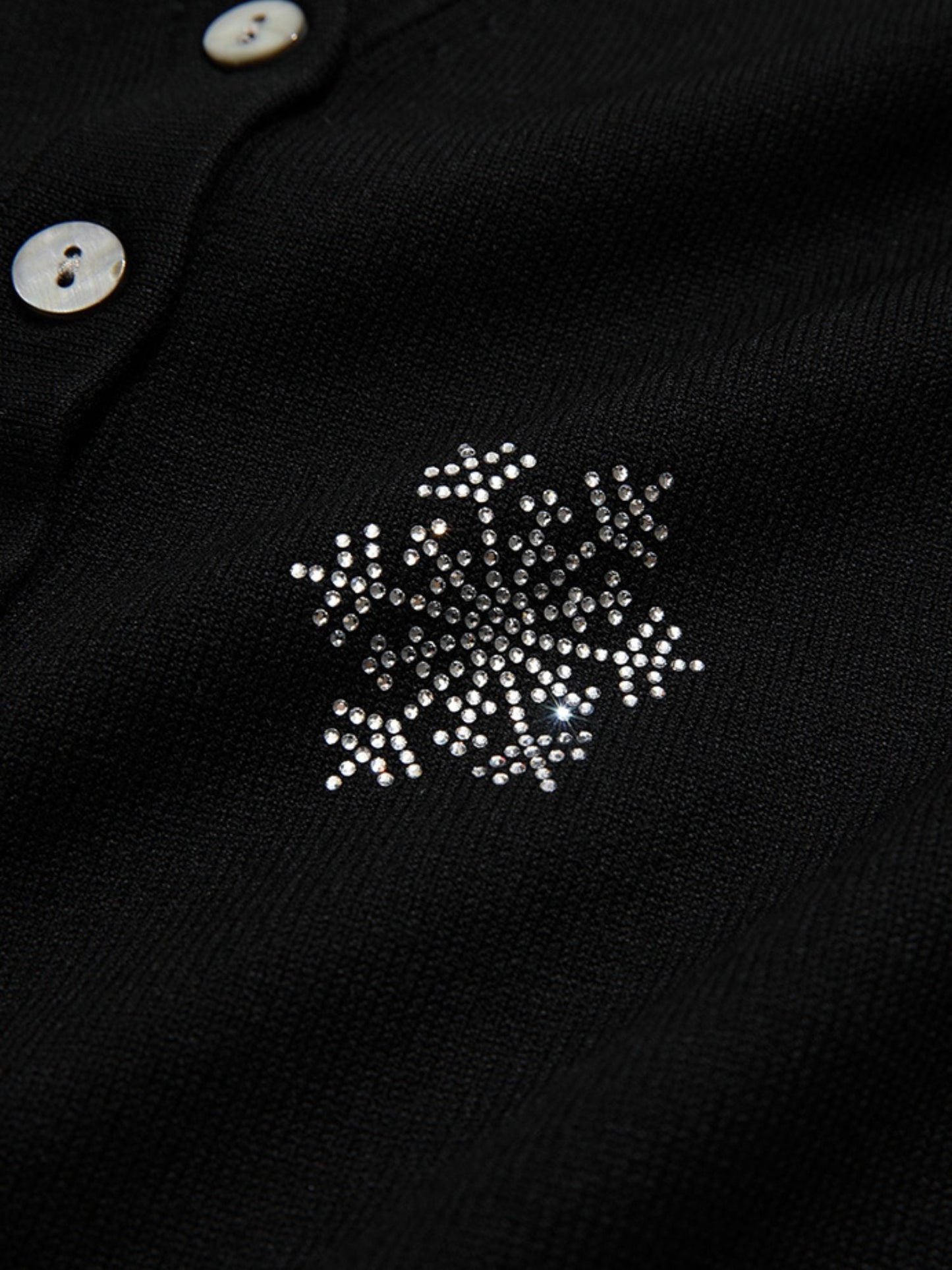 A woman wearing a v-neck cardigan with snowflakes embelishments.