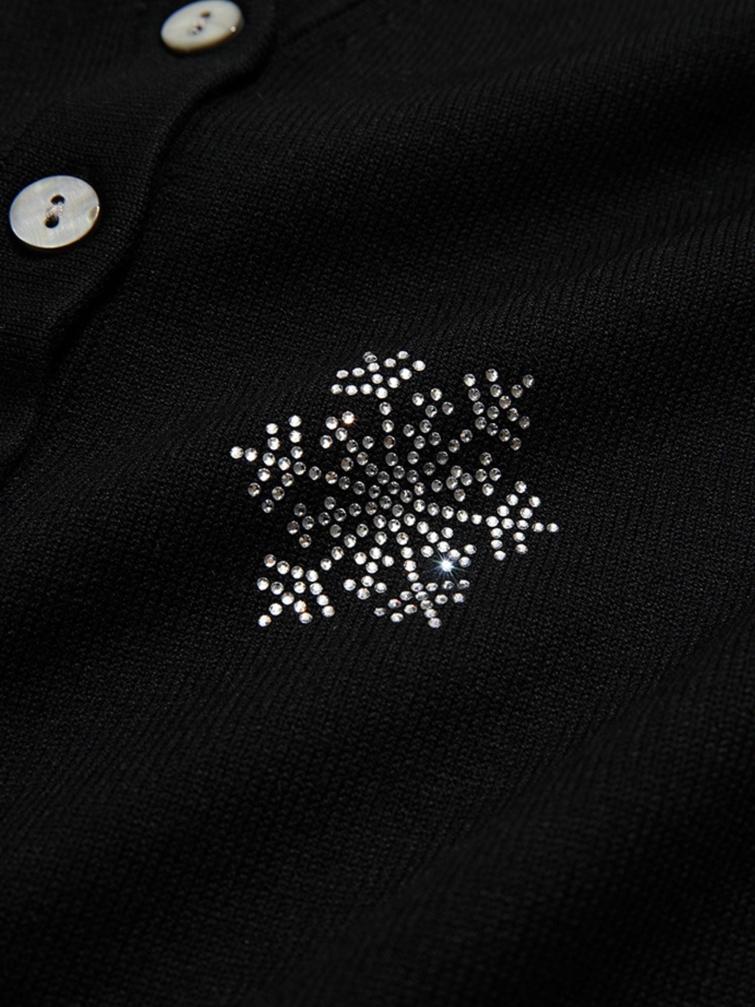 A woman wearing a v-neck cardigan with snowflakes embelishments.