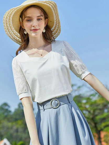 A woman wearing a summer blouse with eyelet ouff sleeves and a square neckline.