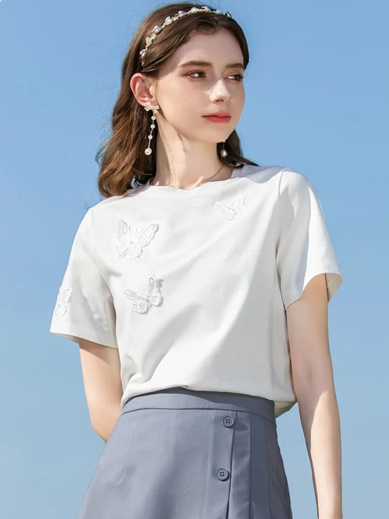 A woman wearing a summer t-shirt with a butterfly embroidery.